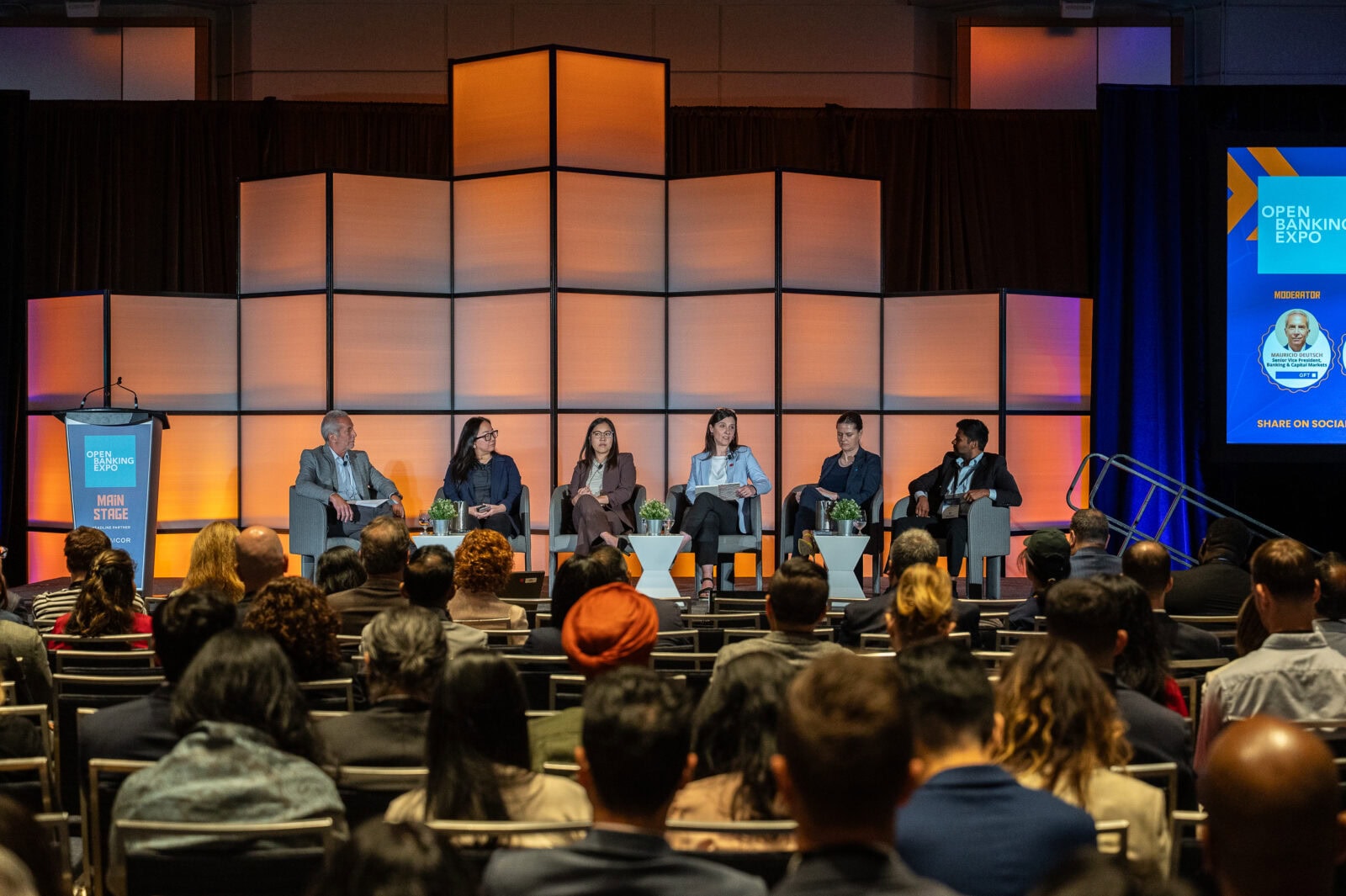 A group of people sitting on stage at a conference.